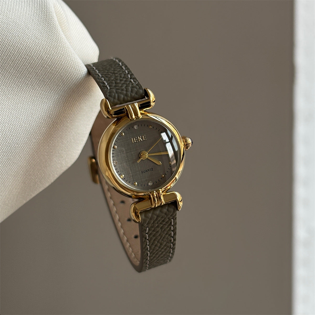 Olive-colored strap watch with a gold round dial, featuring a niche design