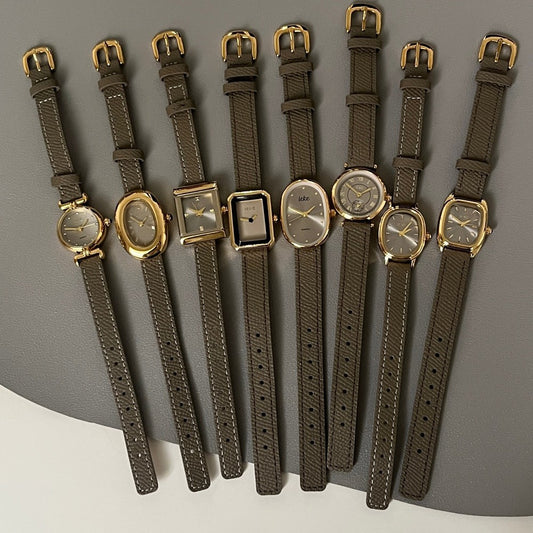 Olive-colored strap watch with a gold oval dial, featuring a niche design
