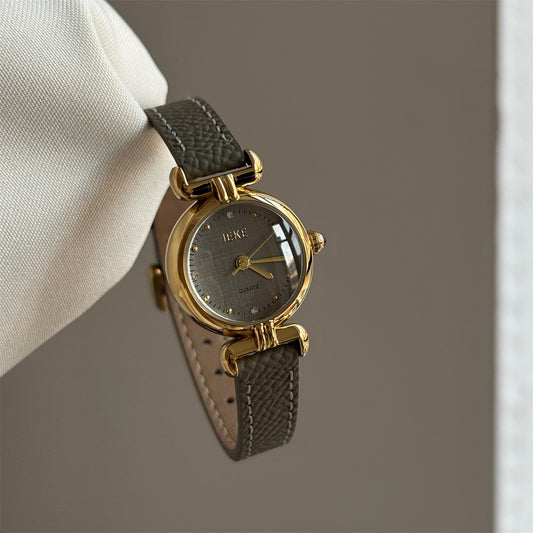 Olive-colored strap watch with a gold round dial, featuring a niche design