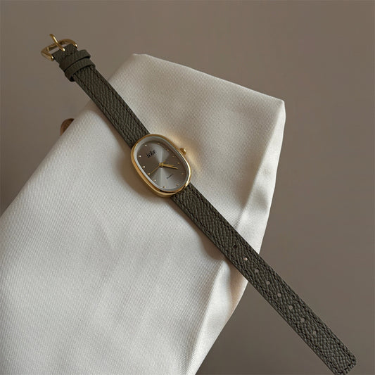 Olive-colored strap watch with a gold oval dial, featuring a niche design
